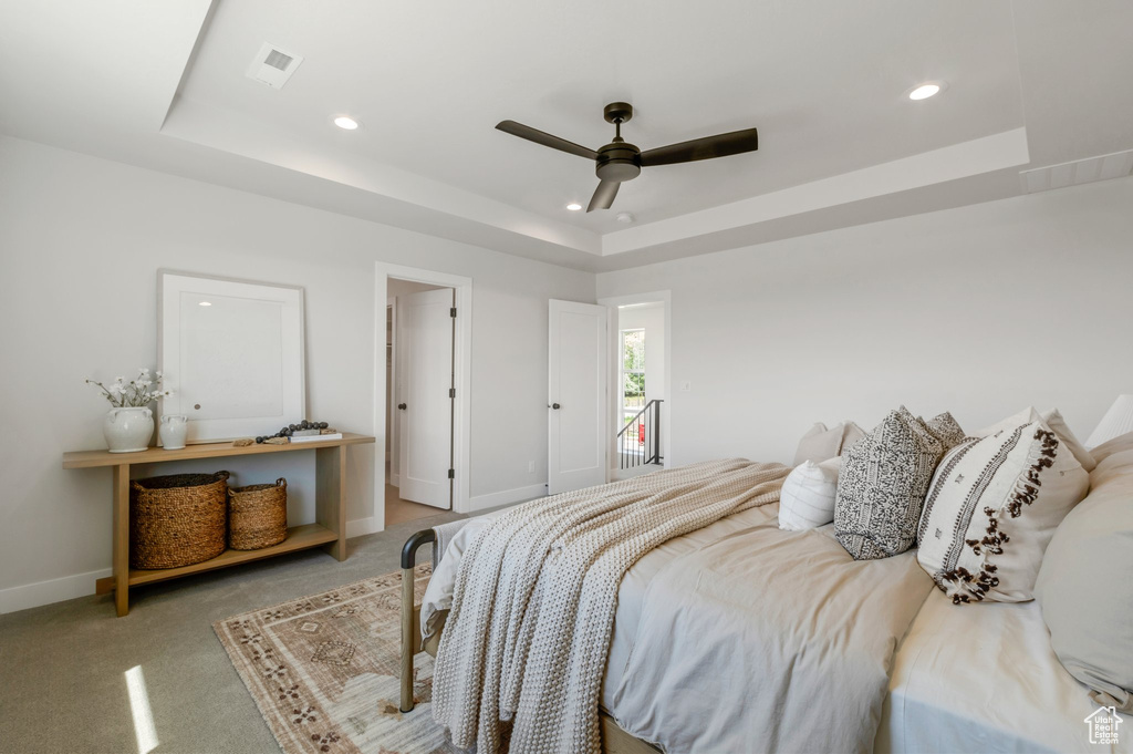 Bedroom featuring a raised ceiling, recessed lighting, light colored carpet, and a ceiling fan