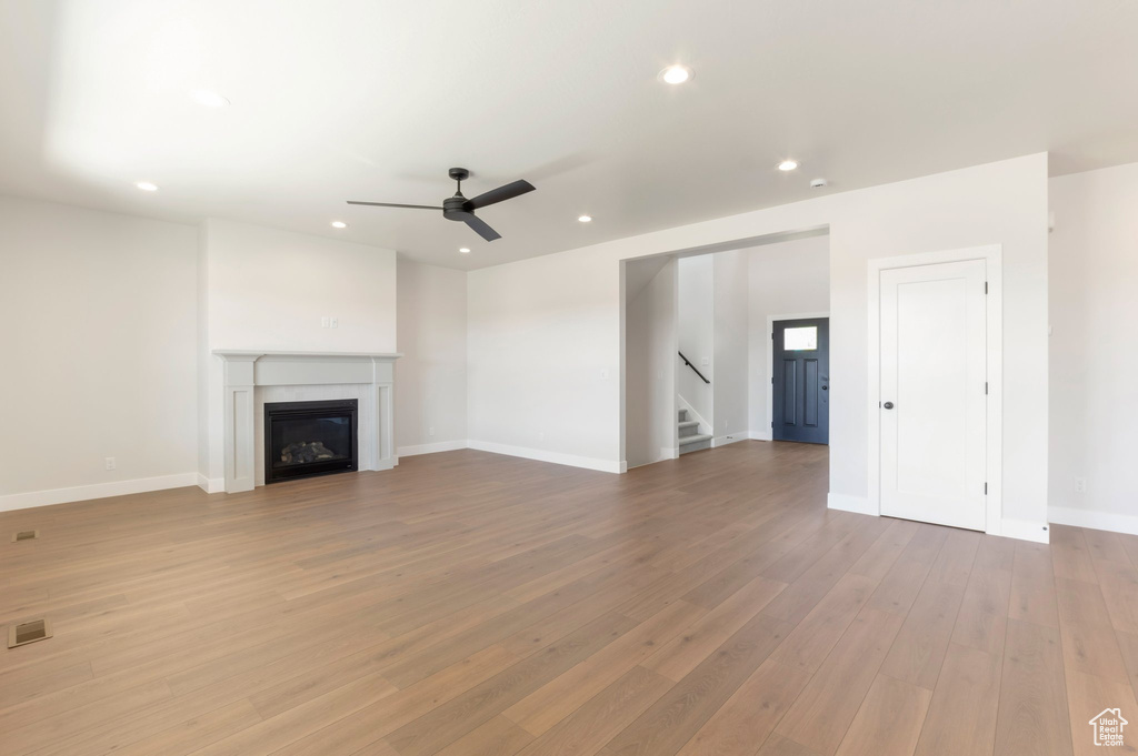 Unfurnished living room with a ceiling fan, stairway, light wood-type flooring, recessed lighting, and baseboards