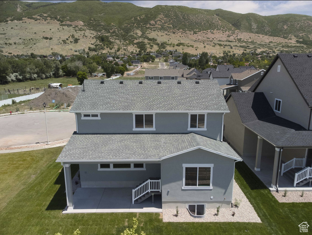 Rear view of property featuring stucco siding, a patio, a mountain view, and a yard