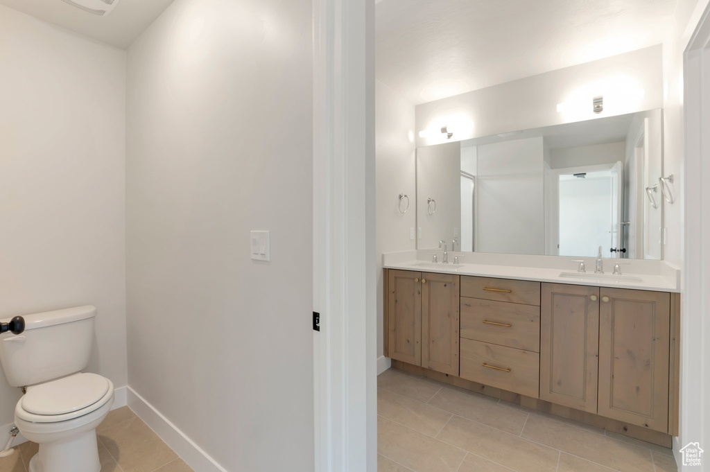 Bathroom with tile patterned flooring, toilet, double vanity, and baseboards