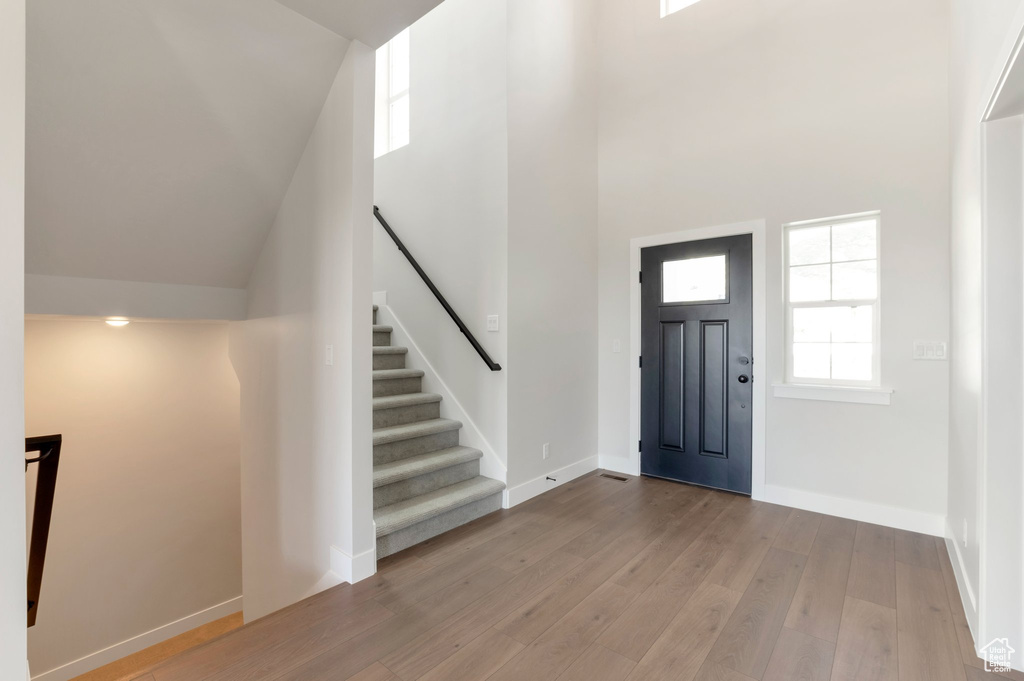 Entryway with wood-type flooring, a high ceiling, healthy amount of natural light, stairway, and baseboards