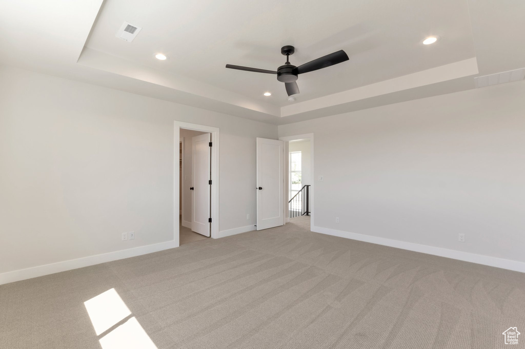 Unfurnished room with a raised ceiling, light carpet, recessed lighting, baseboards, and a ceiling fan
