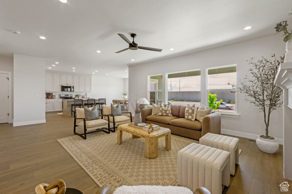 Living area with ceiling fan, wood finished floors, and recessed lighting