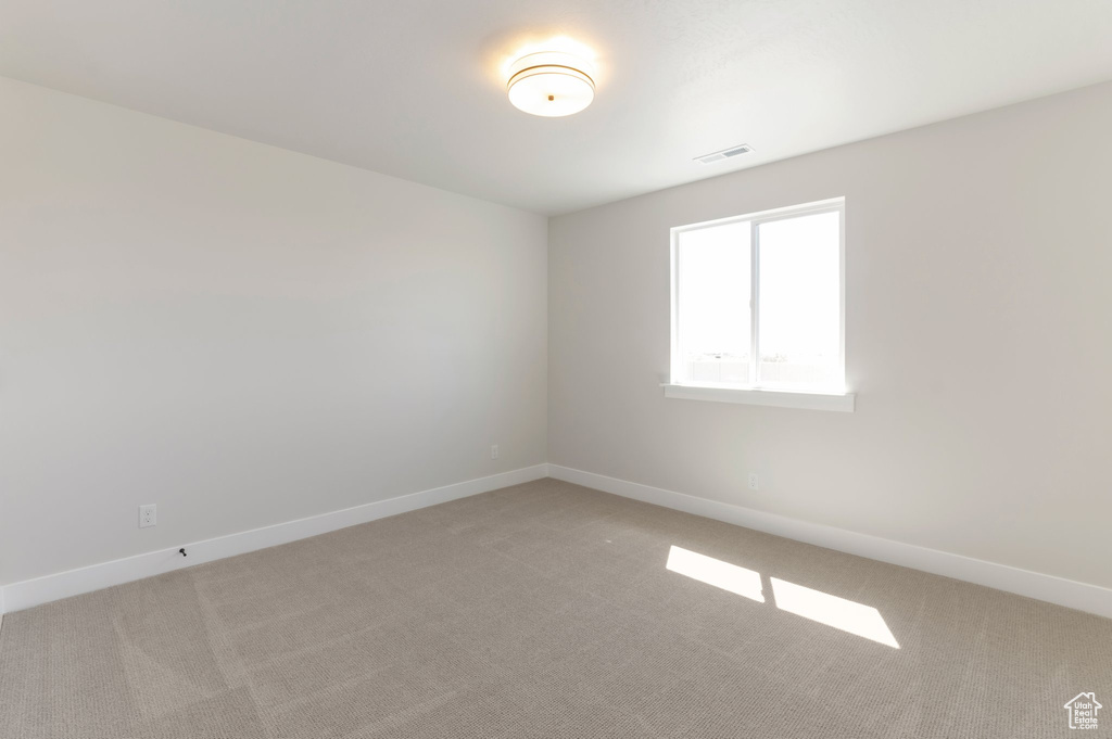 Spare room with light carpet and baseboards