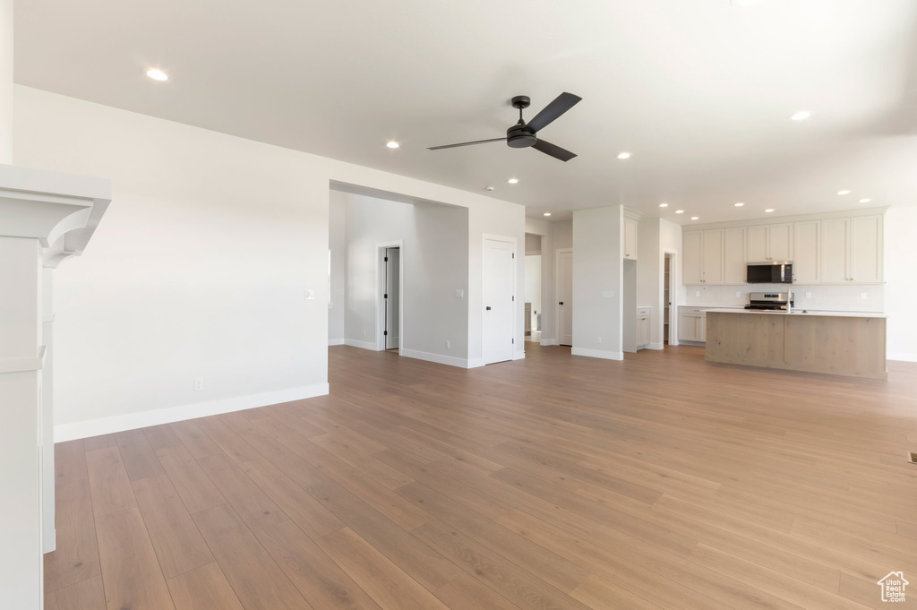 Unfurnished living room featuring ceiling fan, light wood-type flooring, recessed lighting, and baseboards