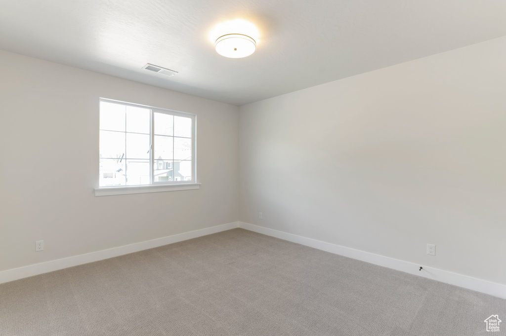 Spare room featuring light carpet and baseboards