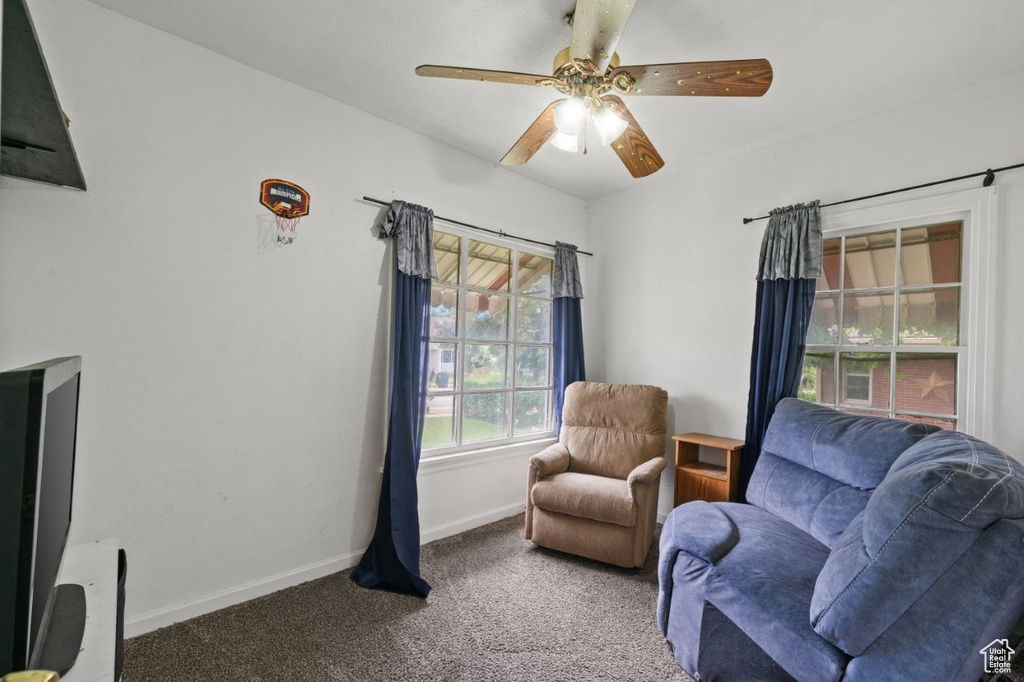 Living area with carpet flooring, baseboards, and ceiling fan