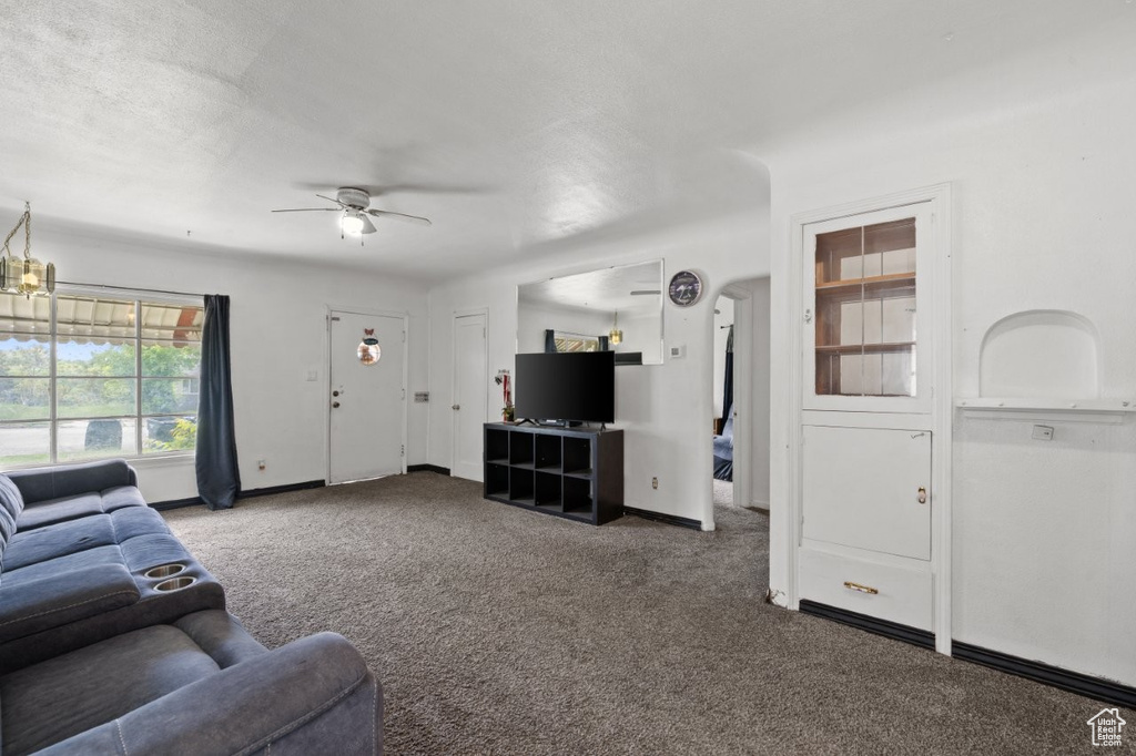 Living room featuring carpet flooring, a ceiling fan, and baseboards