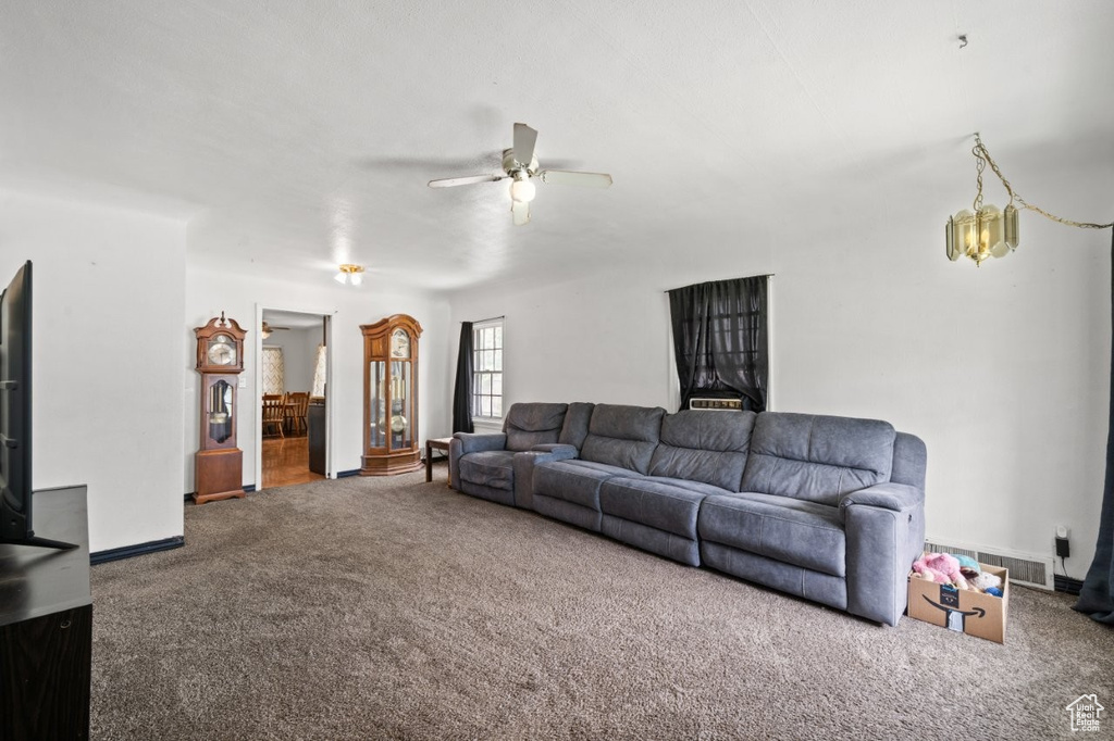 Carpeted living area with a ceiling fan and baseboards