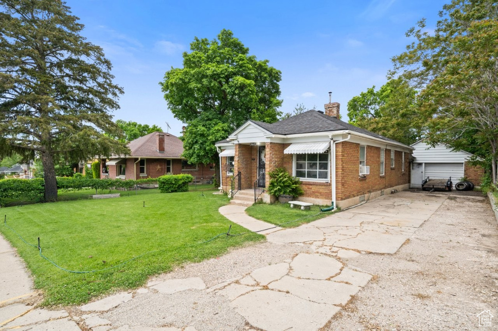 View of front of house with brick siding, a chimney, a front lawn, and roof with shingles