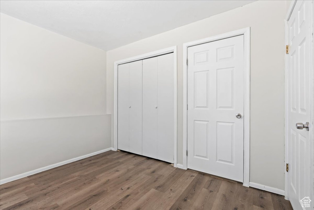 Unfurnished bedroom with wood finished floors, baseboards, and a closet