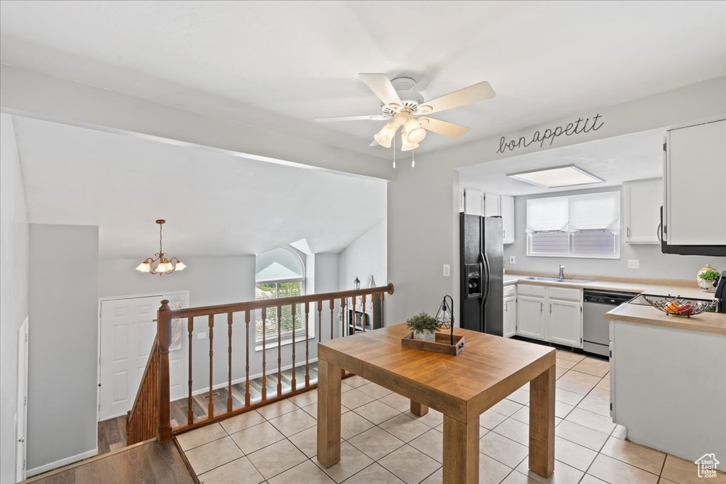 Kitchen featuring black fridge, a sink, dishwasher, light countertops, and white cabinets
