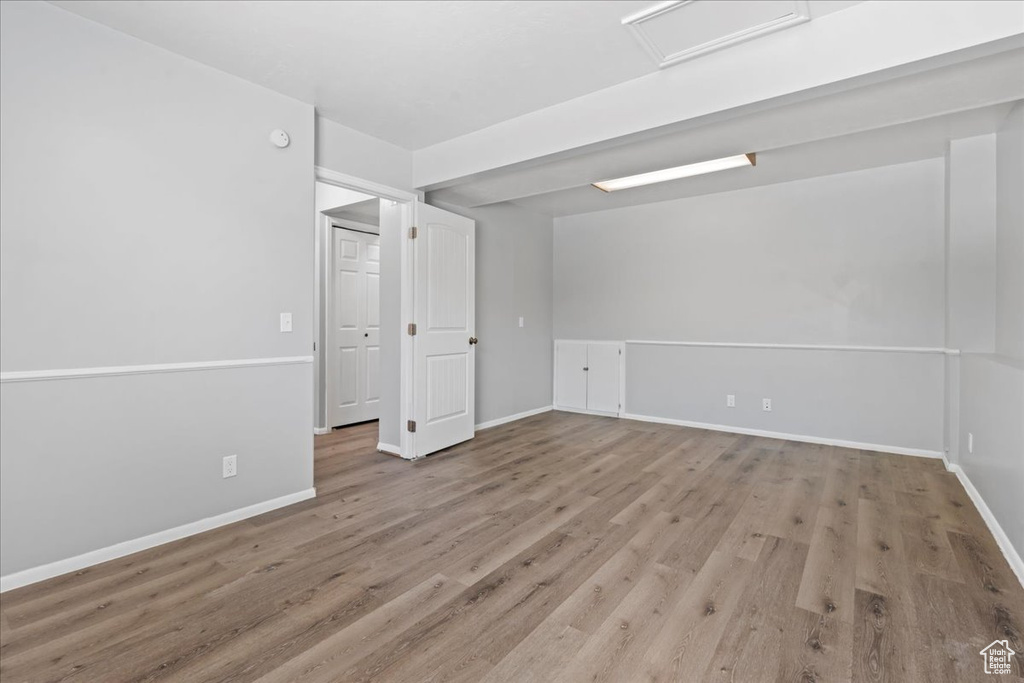 Spare room with wood finished floors, baseboards, and attic access
