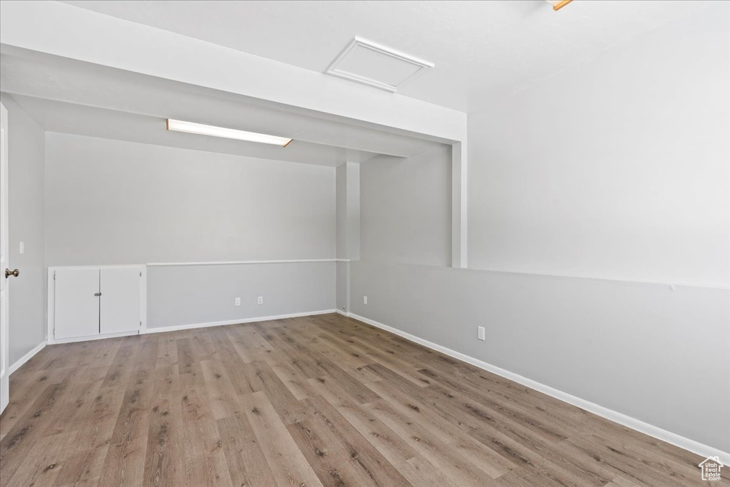 Unfurnished room featuring wood finished floors, baseboards, and attic access