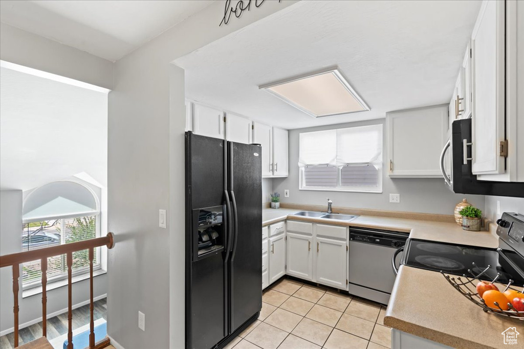 Kitchen with stainless steel appliances, a sink, light tile patterned floors, and white cabinetry