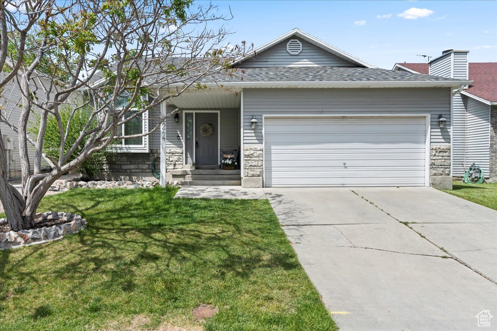 View of front of home featuring an attached garage, concrete driveway, a front yard, roof with shingles, and a chimney