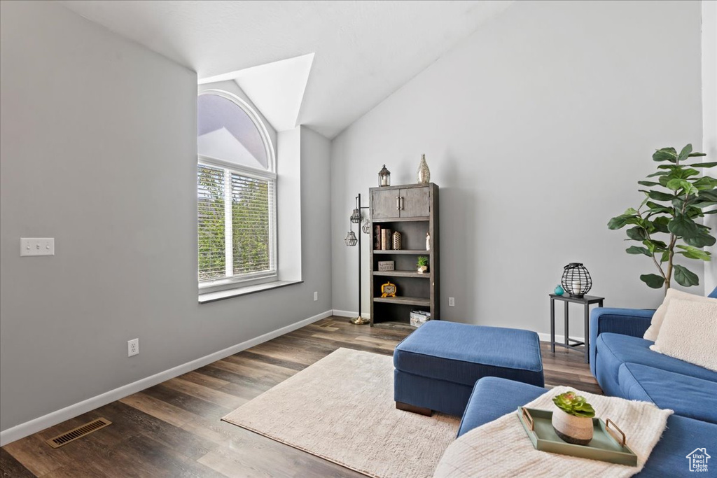 Living area with dark wood finished floors, lofted ceiling, and baseboards