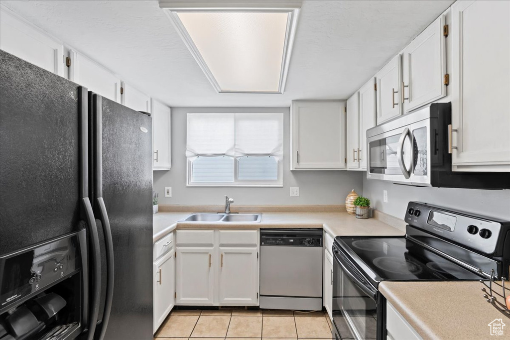 Kitchen with black appliances, a sink, and white cabinets
