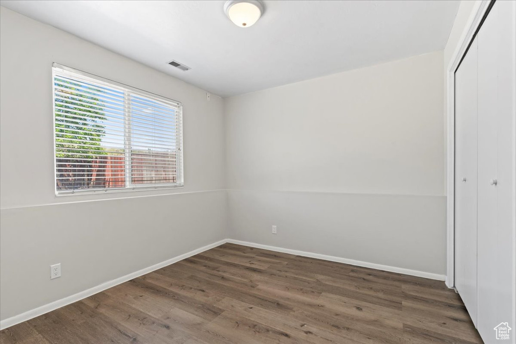 Unfurnished bedroom featuring a closet, wood finished floors, and baseboards