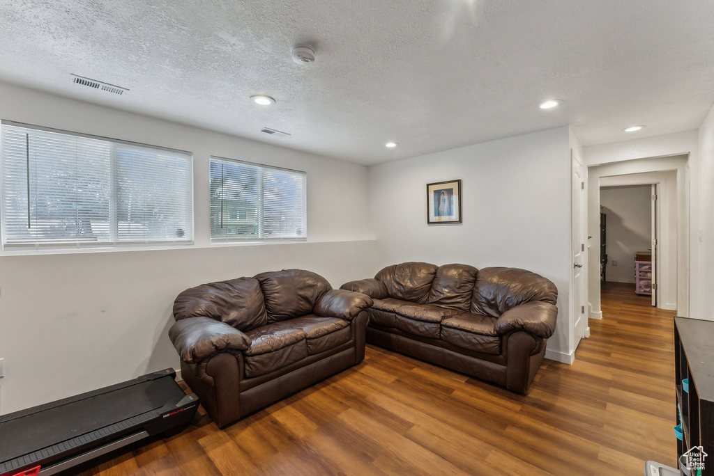 Living room with wood finished floors, a textured ceiling, and recessed lighting