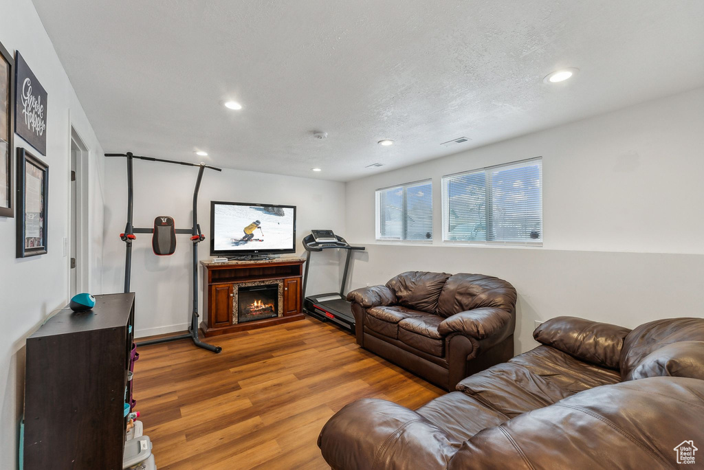 Living area with wood finished floors, recessed lighting, and a lit fireplace