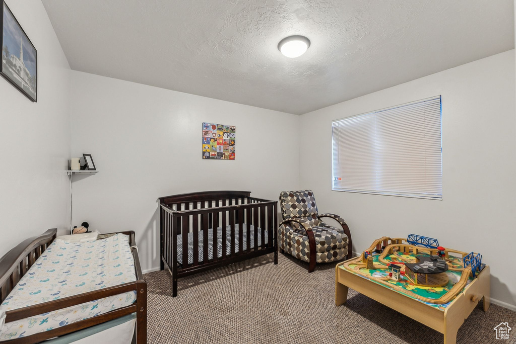 Carpeted bedroom with a textured ceiling and baseboards