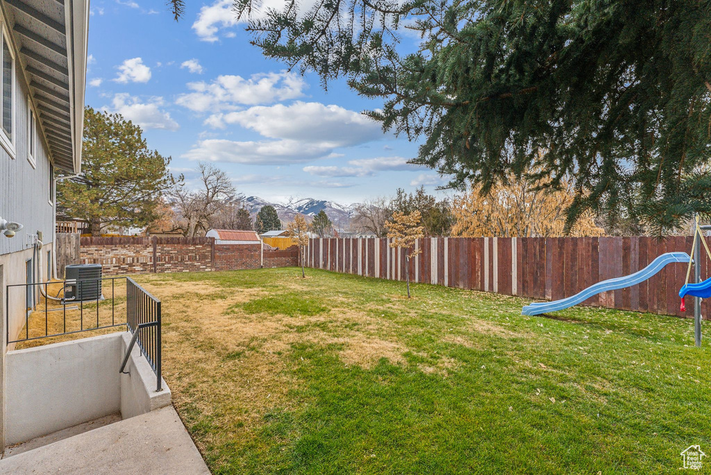 View of yard with central AC unit, a mountain view, and a playground