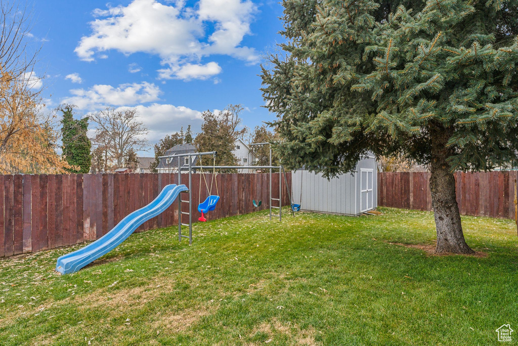 View of yard with a playground, a storage unit, and an outbuilding