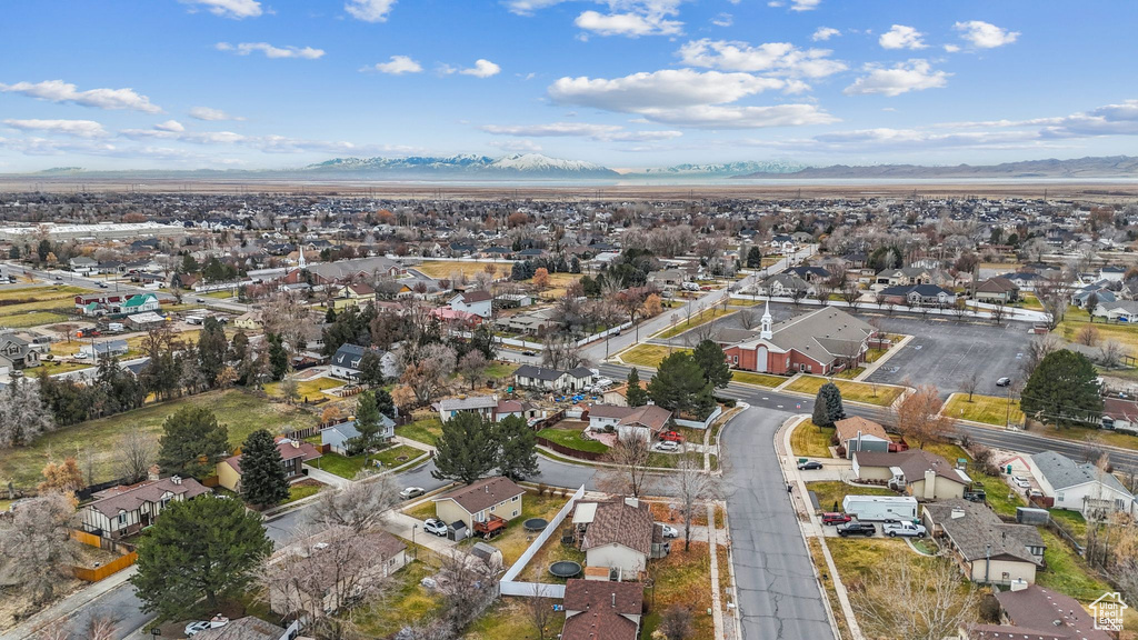 Aerial view of property and surrounding area featuring nearby suburban area and a mountainous background