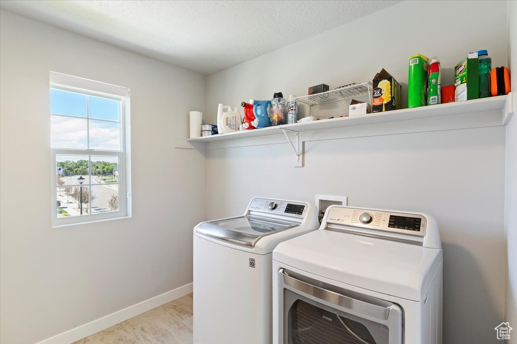 Laundry room featuring separate washer and dryer, baseboards, and a textured ceiling