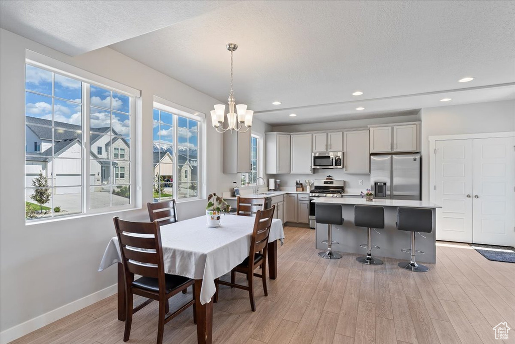 Dining area featuring light wood-style floors, a chandelier, baseboards, recessed lighting, and a textured ceiling
