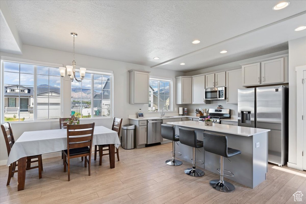 Kitchen featuring appliances with stainless steel finishes, a sink, a textured ceiling, light countertops, and a kitchen island