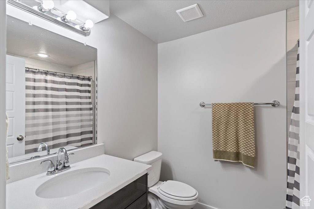 Full bath featuring toilet, a shower with curtain, and vanity