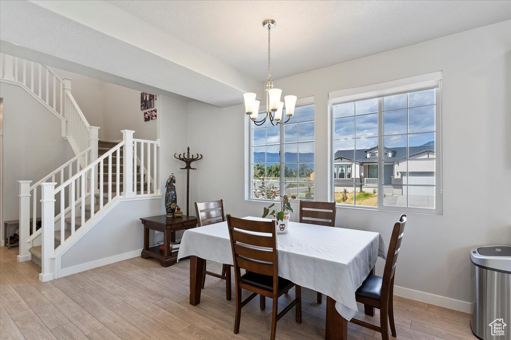Dining area with stairs, light wood finished floors, a chandelier, and baseboards