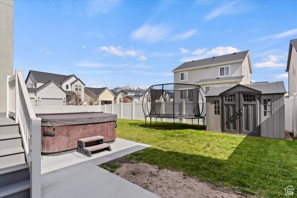 View of yard featuring a hot tub, a trampoline, a residential view, and a patio
