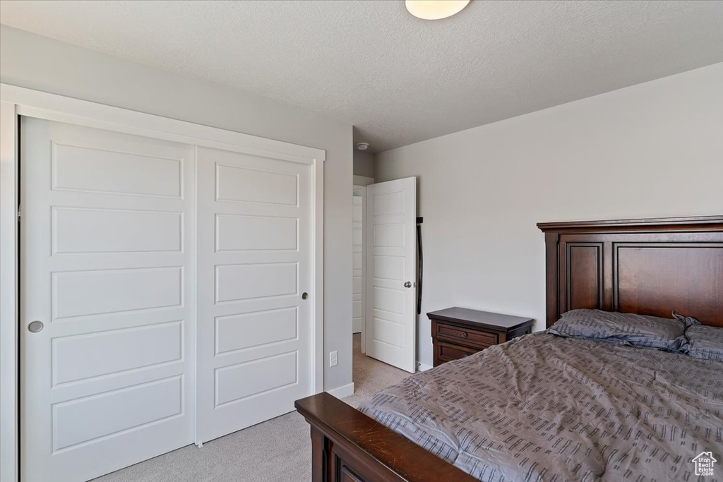 Bedroom with light colored carpet and a closet