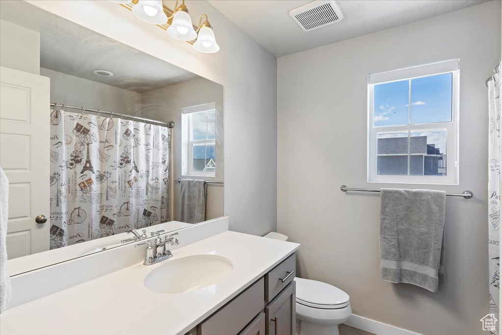 Full bath featuring toilet, vanity, and curtained shower