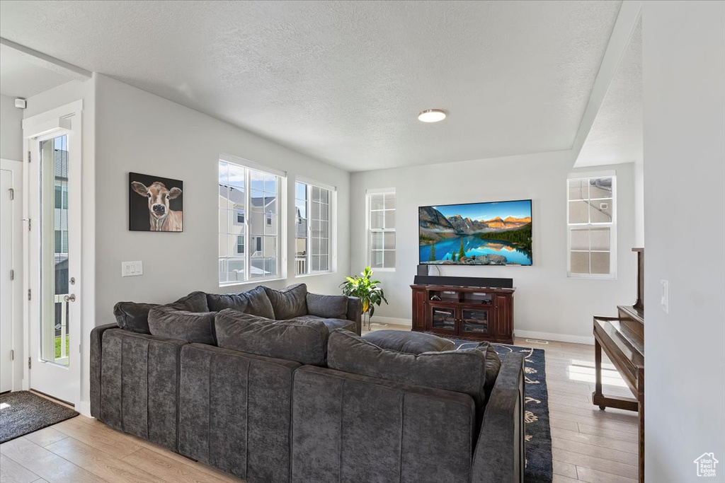 Living room with light wood-style flooring, a textured ceiling, and baseboards