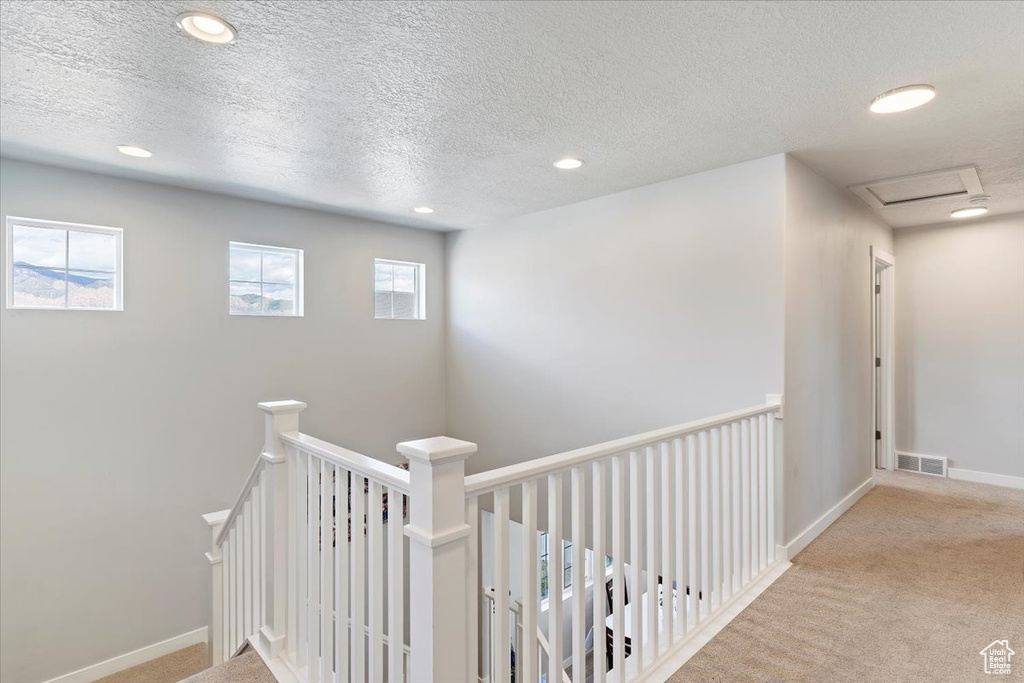 Hall with a textured ceiling, carpet flooring, recessed lighting, baseboards, and an upstairs landing