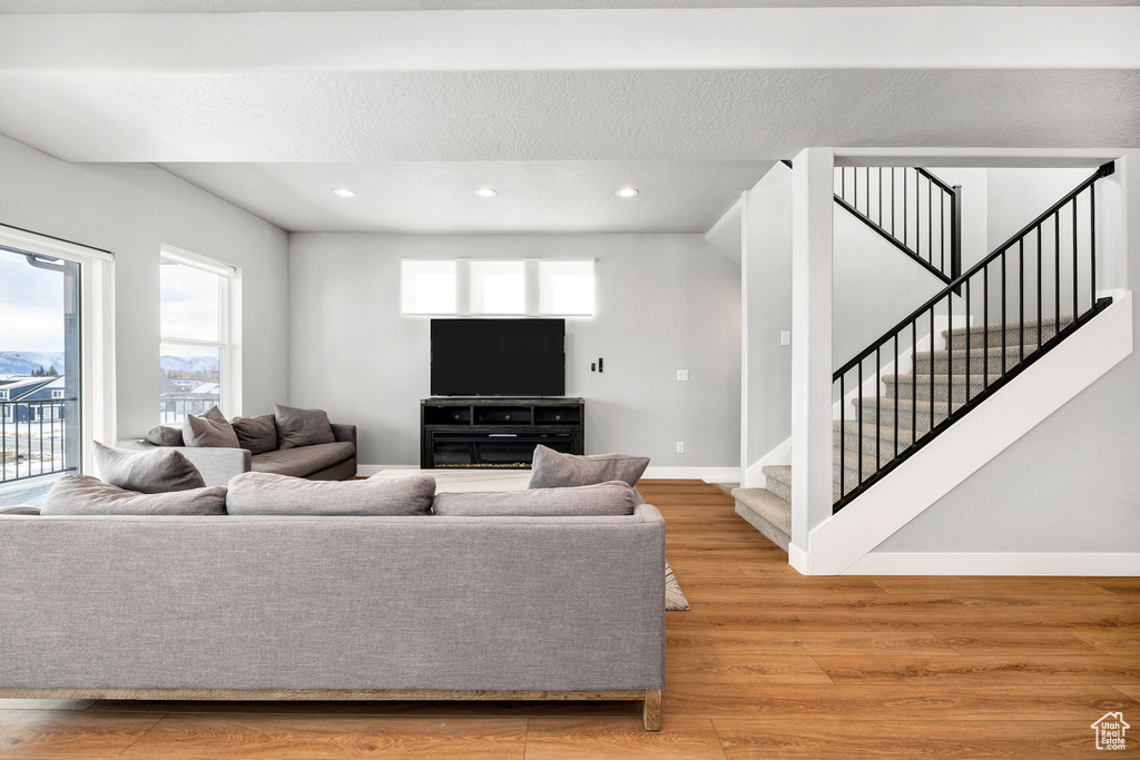 Living area featuring stairway, light wood-style flooring, baseboards, and recessed lighting