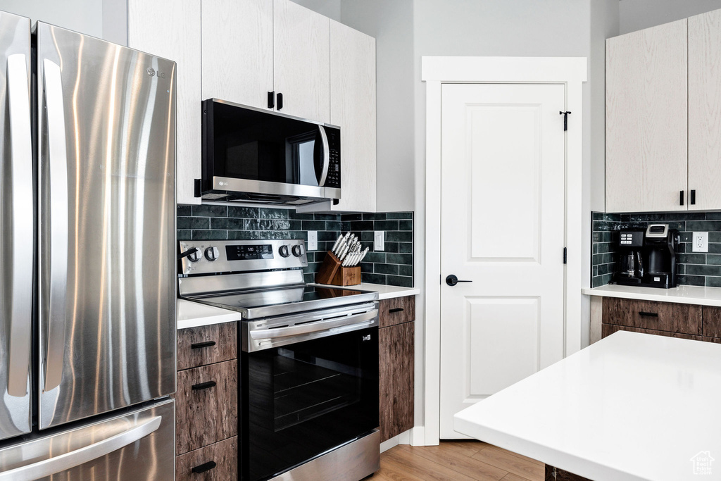Kitchen with appliances with stainless steel finishes, light countertops, tasteful backsplash, and light wood-style floors