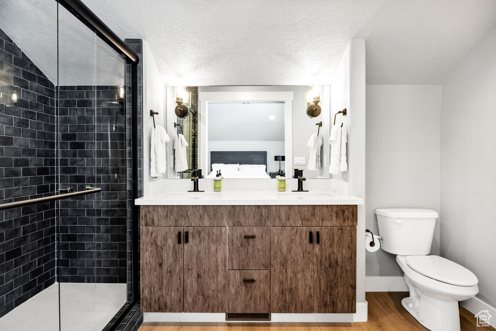 Full bathroom featuring a shower stall, toilet, wood finished floors, connected bathroom, and double vanity