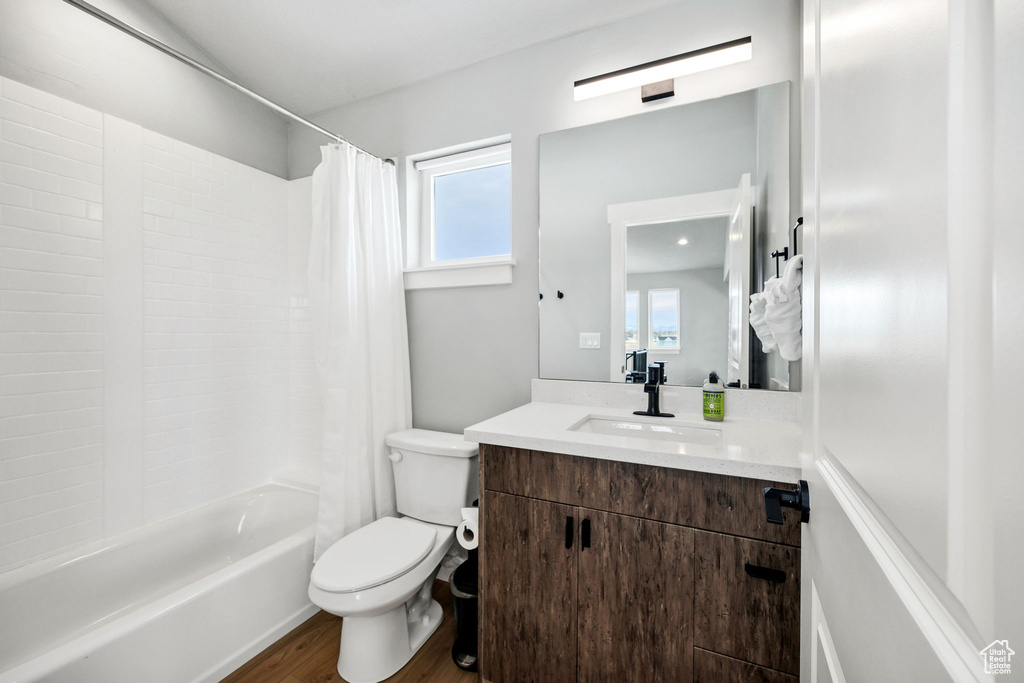Full bath with wood finished floors, toilet, vanity, and shower / bathtub combination with curtain