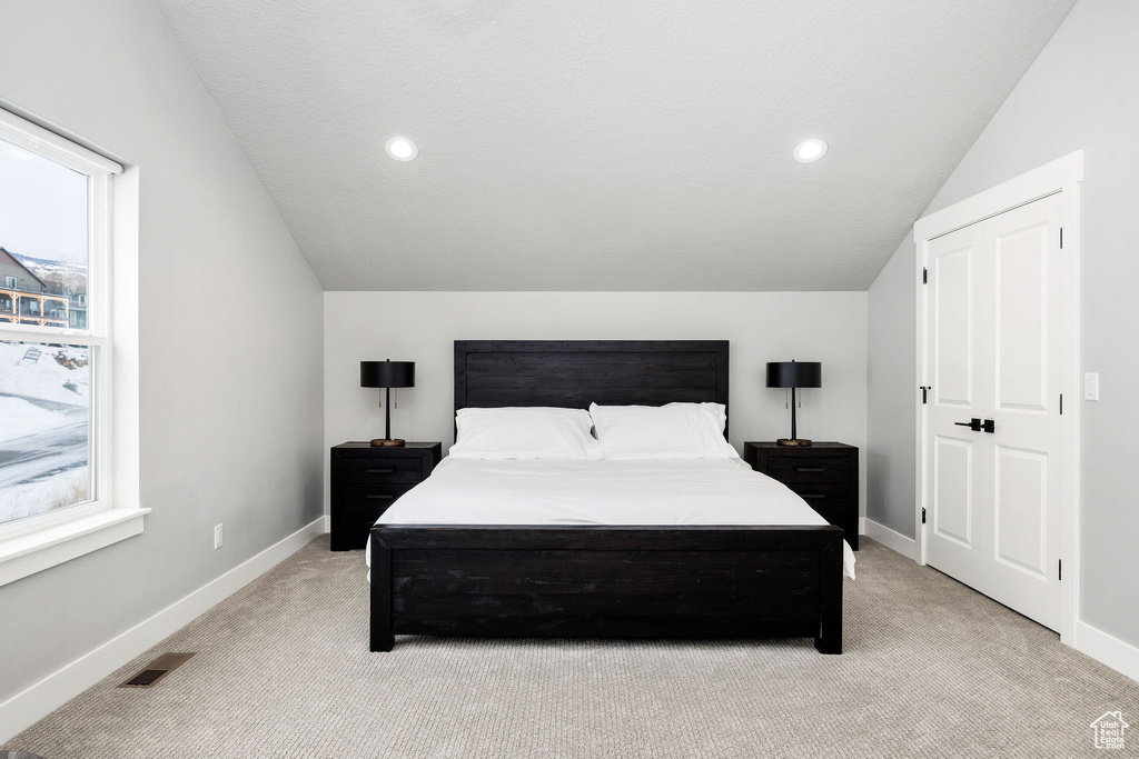 Bedroom featuring light colored carpet, lofted ceiling, baseboards, multiple windows, and recessed lighting