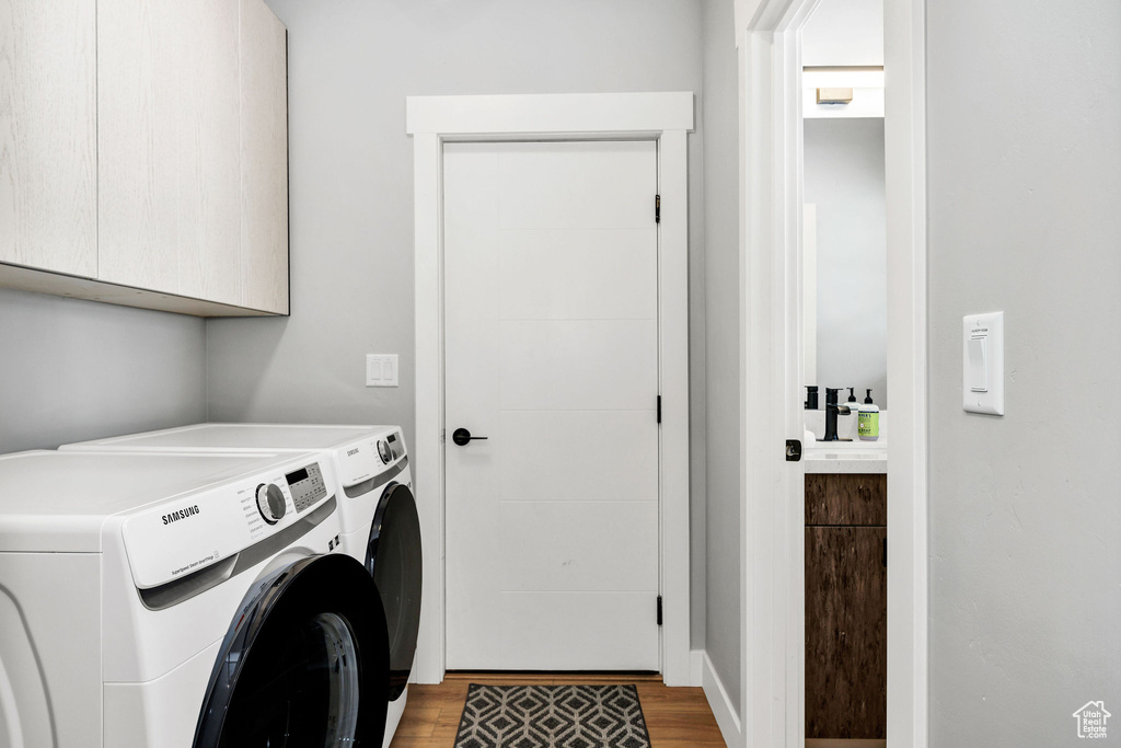 Laundry room with cabinet space, independent washer and dryer, and light wood-style floors