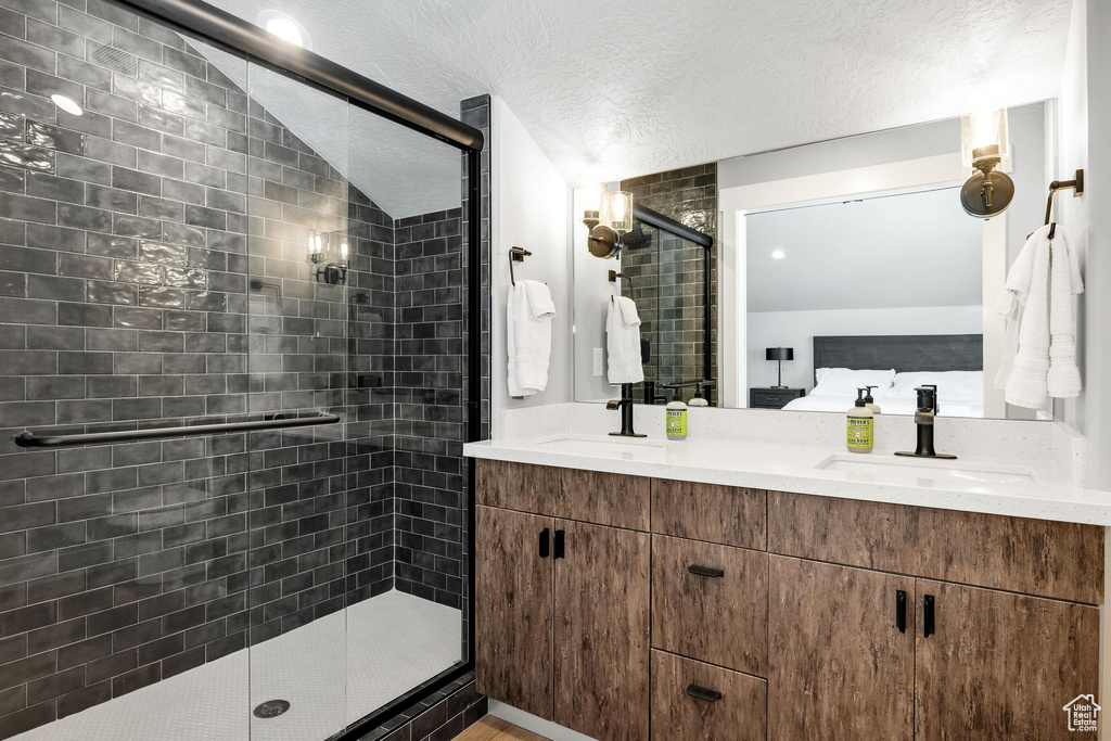 Bathroom with a shower stall, ensuite bath, double vanity, and a textured ceiling