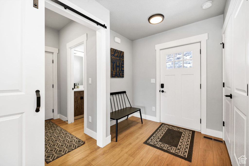 Entryway featuring a barn door, light wood finished floors, and baseboards
