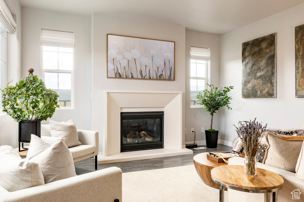 Living area with wood finished floors, a glass covered fireplace, and baseboards