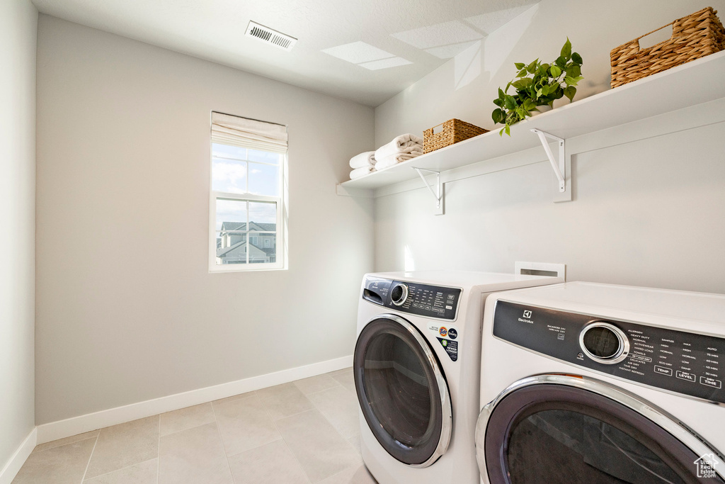 Laundry room with washer and dryer, baseboards, and light tile patterned floors