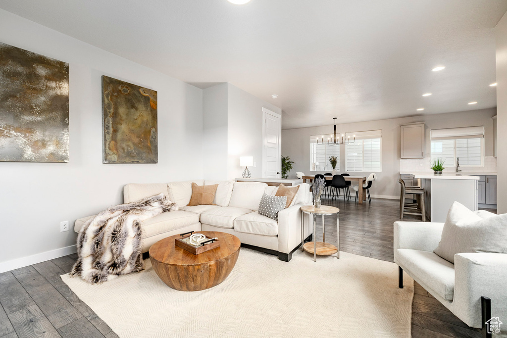 Living area with a chandelier, dark wood-type flooring, baseboards, and recessed lighting
